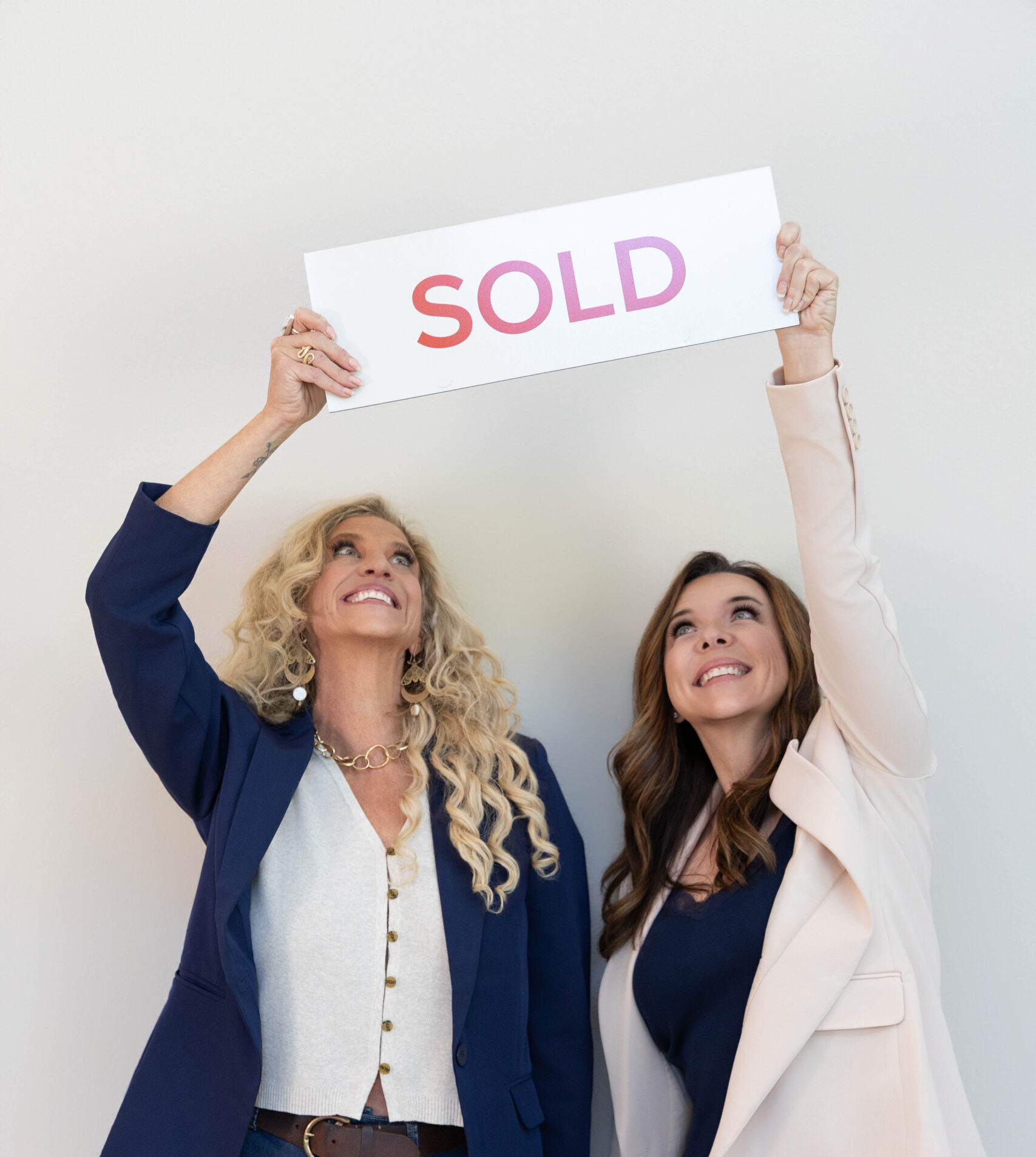 Jessica Luginbill and Misti Stewart of Luginbill Homes holding a SOLD sign for a Northern Colorado real estate transaction